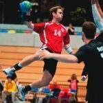 man holding ball while jumping near three mne