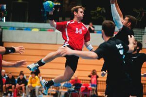 man holding ball while jumping near three mne