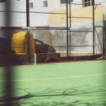 a tennis court with a car parked in the background